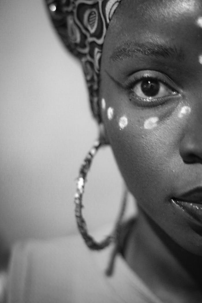 Close-up black and white portrait of woman with traditional makeup and patterned headscarf.