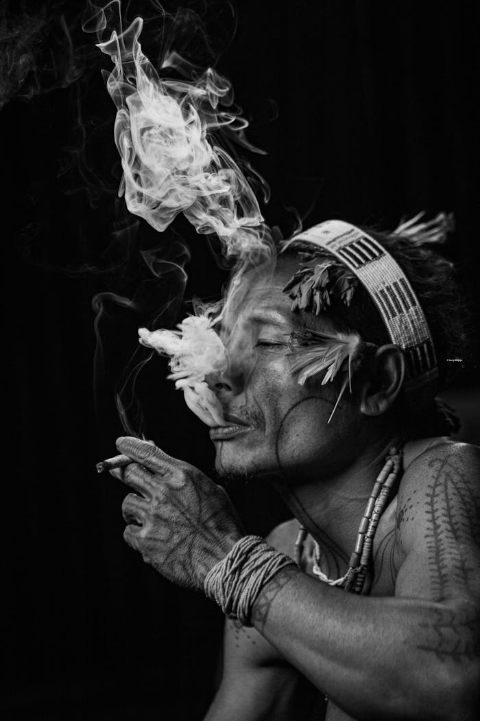 Portrait of a West Sumatran man in traditional attire smoking, creating dramatic smoke patterns.