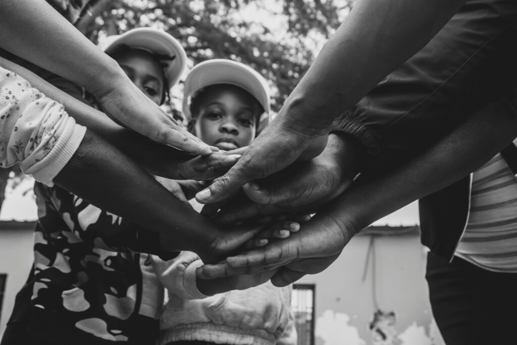 A group of diverse hands joined in solidarity, symbolizing unity and community support in Luanda, Angola.