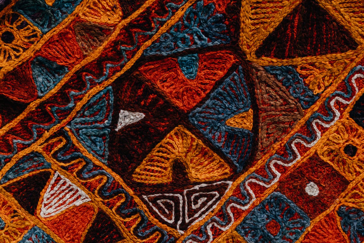 Intricate colorful carpet texture with artistic patterns in detailed close-up view.